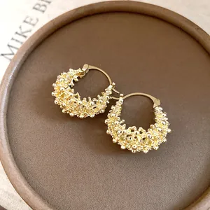 Detailed view of French style gold hoop earrings featuring an intricate bubble texture.
