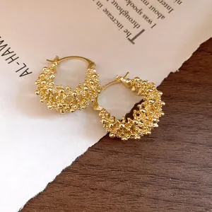 Detailed view of gold-tone French hollow basket-weave hoop earrings with textured finish