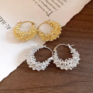 Close-up detail of French hollow textured hoop earrings in gold and silver finishes.
