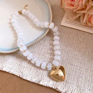 Elegant white resin beaded necklace featuring a polished gold-tone heart pendant.