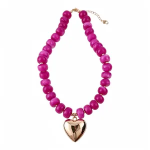 Vibrant fuchsia resin beaded necklace with a polished gold heart pendant on white background.