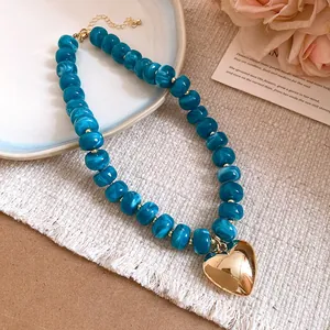 Detailed macro view of marbled blue resin beads and a polished gold heart pendant