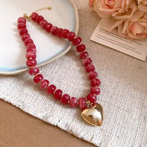 Detail shot of a red resin beaded necklace with a large golden heart-shaped pendant