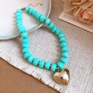 Detail view of turquoise resin beads and a polished gold heart pendant necklace.