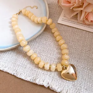 Detailed view of the creamy resin beads and high-polish gold heart pendant on necklace