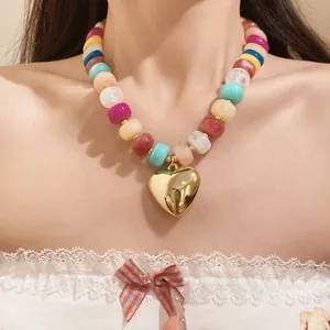 Detailed view of a vibrant colorful resin bead necklace featuring a polished gold heart pendant.