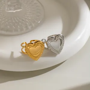 Close-up of stainless steel heart locket rings with vintage floral engraving detail.