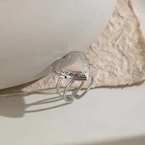 Close-up of silver stainless steel heart locket ring with vintage engravings and adjustable band.