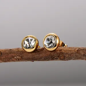 Dettaglio di eleganti orecchini a lobo in acciaio placcato oro con zircone tondo