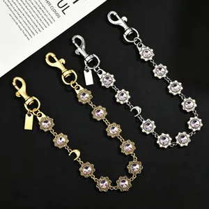 Macro view of flower-shaped rhinestone bag extension chains in gold and silver finish.