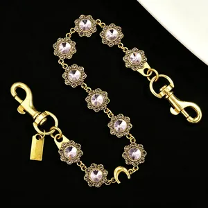 Detail of luxury gold metal bag chain with sparkling rhinestones and flower links