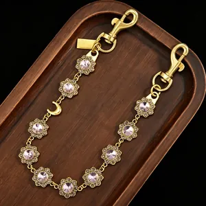 Close-up view of a luxury gold bag extension chain featuring pink rhinestone flowers