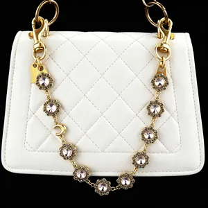 Detail shot of a gold rhinestone bag chain strap with floral crystals and moon charm.