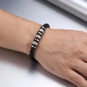 Close-up view of a men's braided black leather bracelet featuring knurled steel beads