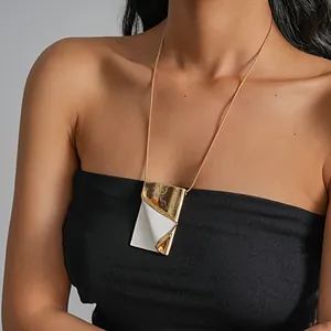 Close-up of a stylish gold and white metallic book-shaped pendant necklace on a model.