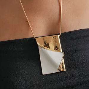 Close-up of a gold and white enamel page-flip book pendant necklace worn on a model.