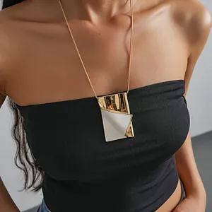 Close-up of a gold-plated book pendant necklace with white enamel details.