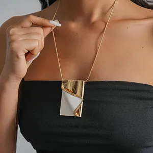 Detail view of a creative gold-toned metal necklace with white enamel page-turning design