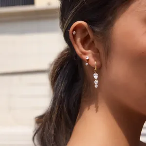 Détail de boucles d'oreilles plaquées or 18 carats avec pompons en zircone sur l'oreille.