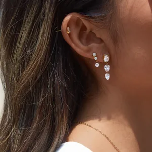 Gros plan de boucles d'oreilles en acier doré 18K avec pierres CZ sur l'oreille d'un modèle