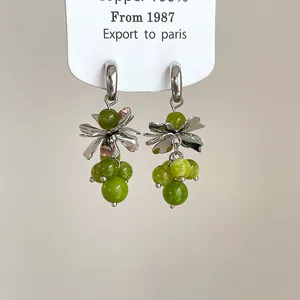 Detailed view of vintage-style flower earrings with silver petals and green beads.