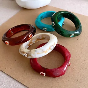 Dikke kleurrijke hars armbanden met vierkante strass accenten op een kraft achtergrond