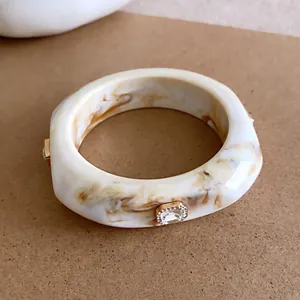 Elegante crème marmeren hars armband met sprankelende goudkleurige strass accenten