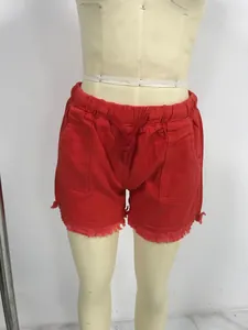 Front view of high-waist red denim shorts with elastic drawstring and fringe hem