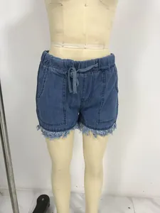 Close-up detail of casual blue denim shorts with a frayed fringe hem and elastic waist.
