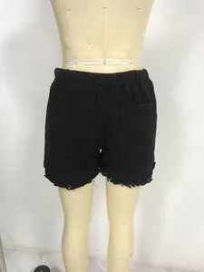 Rear view of black high-waisted denim shorts for women with elastic waist and fringe