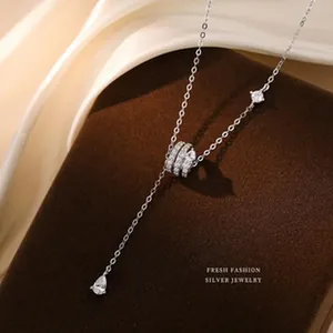 Dettaglio ravvicinato di una collana in argento con pendente ad anello e pietra a goccia.