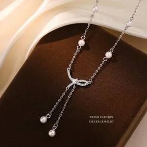 Elegante collana in argento con perle bianche e ciondolo a fiocco su espositore