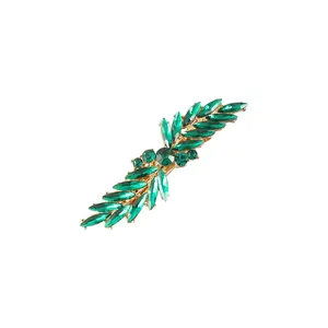 Detail view of a golden hair clip featuring sparkling green leaf-shaped rhinestones.