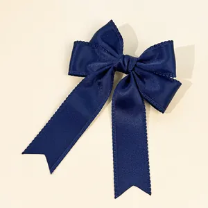 Detailed view of a navy blue ribbon hair bow with scalloped edges and elegant long streamers