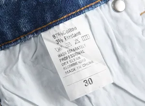 Gros plan sur l'étiquette d'entretien d'un jean bleu pour homme montrant les matières.