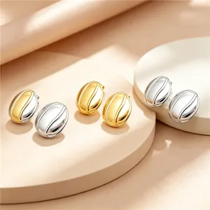 Détail de boucles d'oreilles en acier titane en forme de grain de café, or et argent