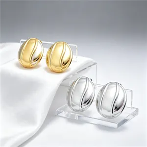 Détail de boucles d'oreilles ovales en acier titane avec finitions or et argent
