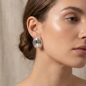 Gros plan détaillé d'une boucle d'oreille ovale argentée rayée sur l'oreille d'un modèle