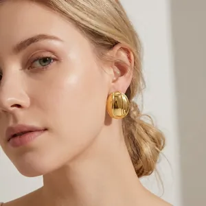 Gros plan d'une femme portant de grandes boucles d'oreilles ovales dorées.
