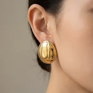 Gros plan détaillé de boucles d'oreilles ovales dorées avec une texture rainurée