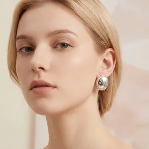 Gros plan d'un mannequin portant des boucles d'oreilles ovales en acier au titane