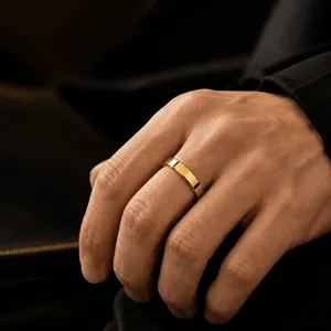 Nahaufnahme eines polierten goldfarbenen Edelstahlrings an einem männlichen Finger