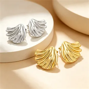 Macro detail of textured shell-shaped titanium steel earrings in gold and silver finish