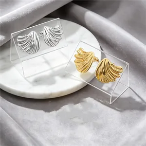 Detailed view of brushed metal fan-shaped earrings in gold and silver finishes