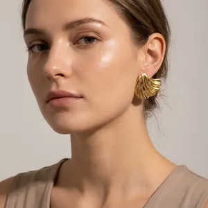 Detailed view of oversized 18K gold-plated brushed leaf-shaped titanium steel earrings on a model.