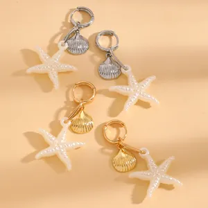 Gros plan sur des boucles d'oreilles pendantes étoile de mer et coquillage chic