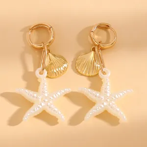 Gros plan macro de boucles d'oreilles créoles dorées avec étoile de mer et breloques coquillages