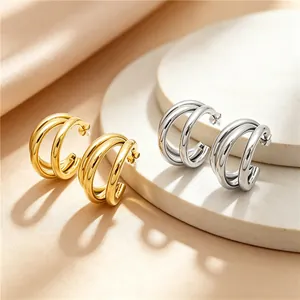 Close-up of gold and silver triple-layered C-shaped stainless steel hoop earrings