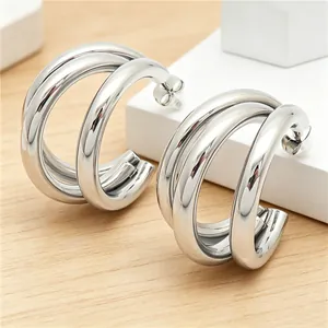 Close-up of minimalist stainless steel triple hoop C-shaped earrings in silver finish