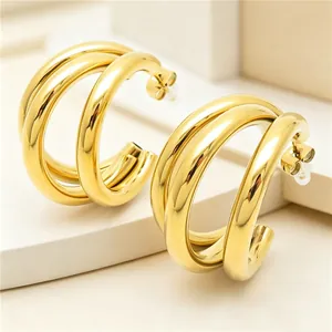 Close-up of gold plated stainless steel triple hoop earrings with minimalist C-shape.